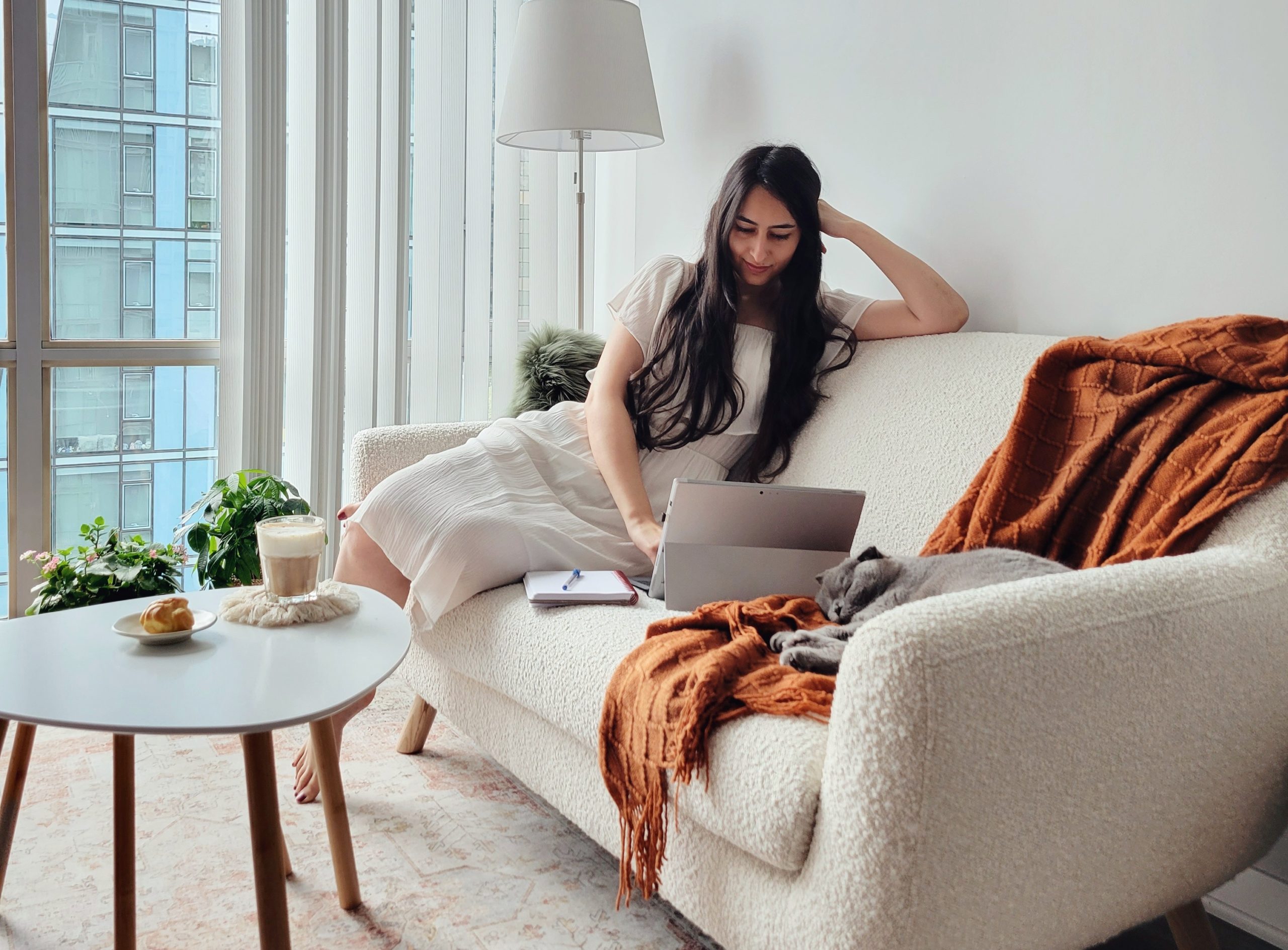 woman sitting on sofa working with laptop